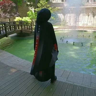 Muslima Fit en habit traditionnel marchant près d'un bassin avec des jets d'eau.
