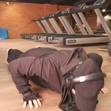 Coach Rachida fait des pompes dans une salle de sport en hijab de sport.