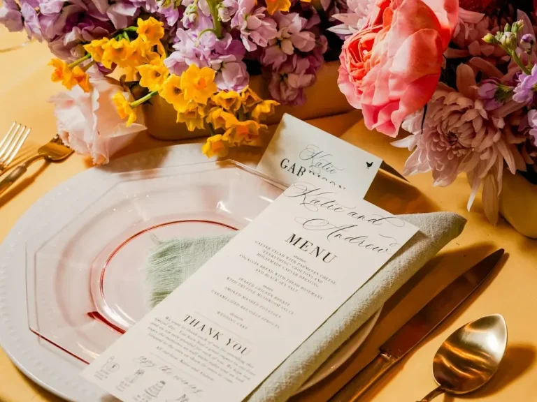 Assiette dressée avec un menu, des fleurs colorées en arrière-plan.