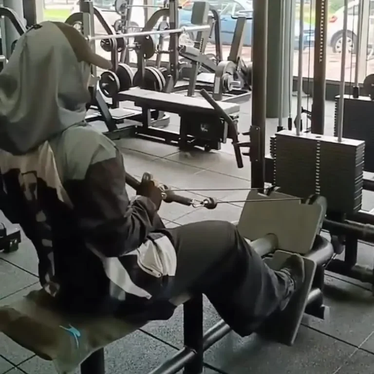 Personne utilisant un appareil de musculation pour les exercices de tirage assis dans une salle de gym.