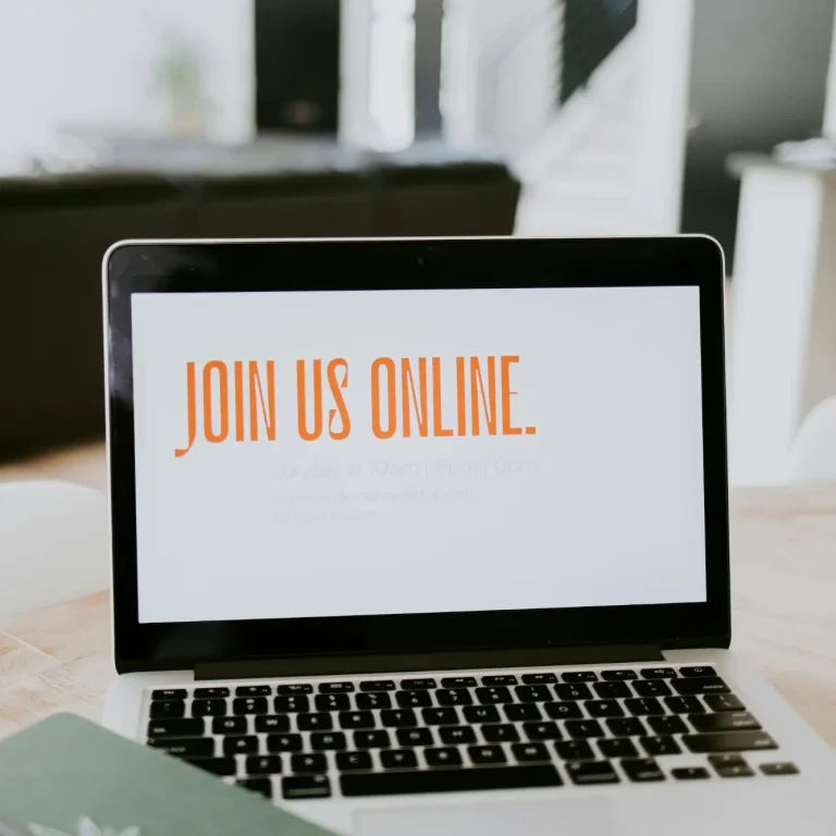 Ordinateur portable affichant le message "JOIN US ONLINE." sur un fond clair.