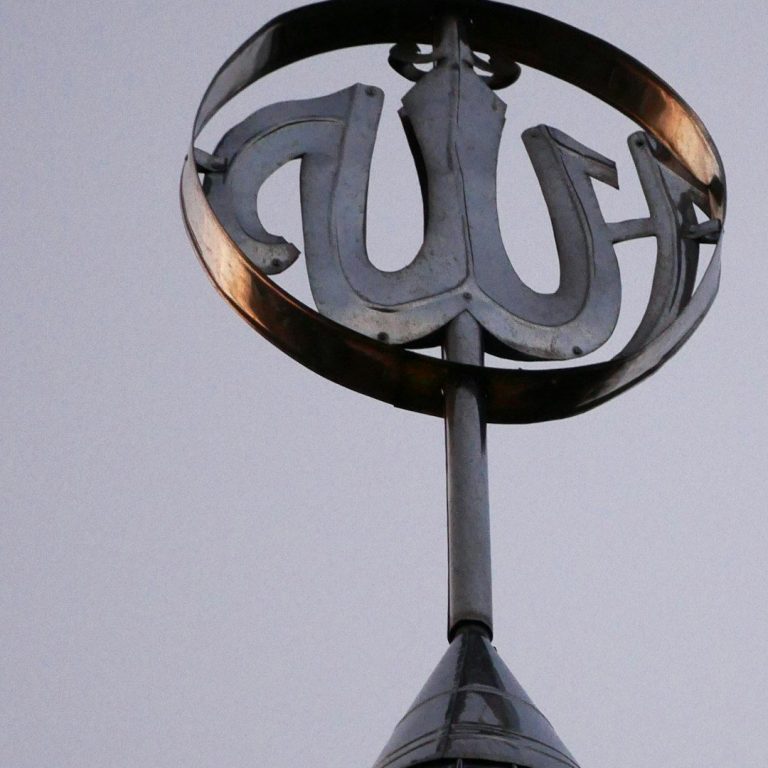 Symbole en métal avec inscription stylisée sur un sommet de bâtiment.
