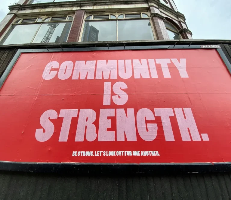 Panneau rouge avec le texte "COMMUNITY IS STRENGTH" en grandes lettres blanches.