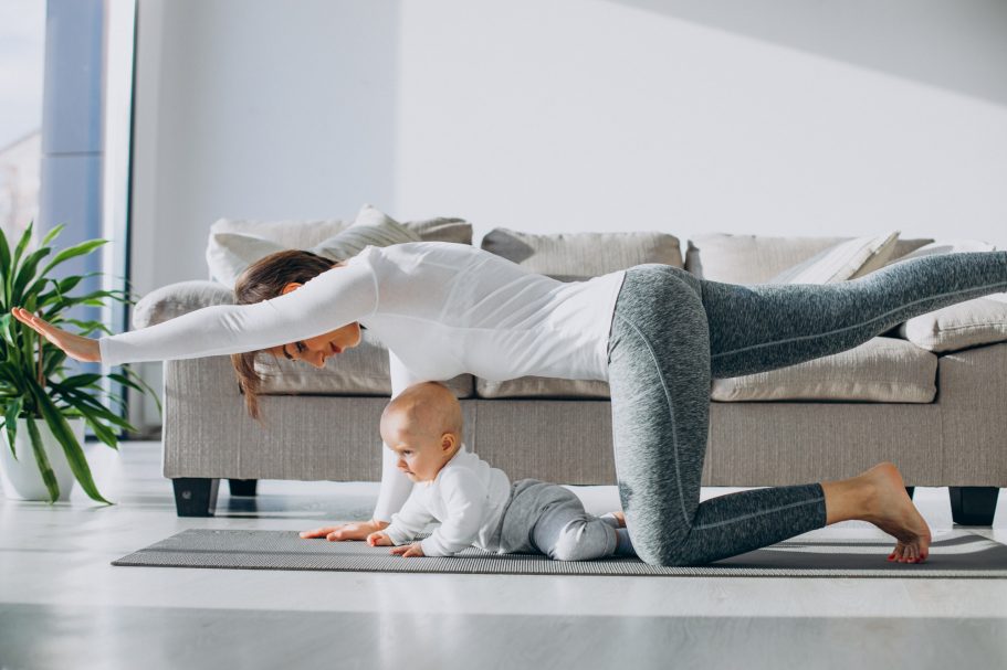 Femme en position de yoga avec un bébé sur un tapis dans un intérieur lumineux.