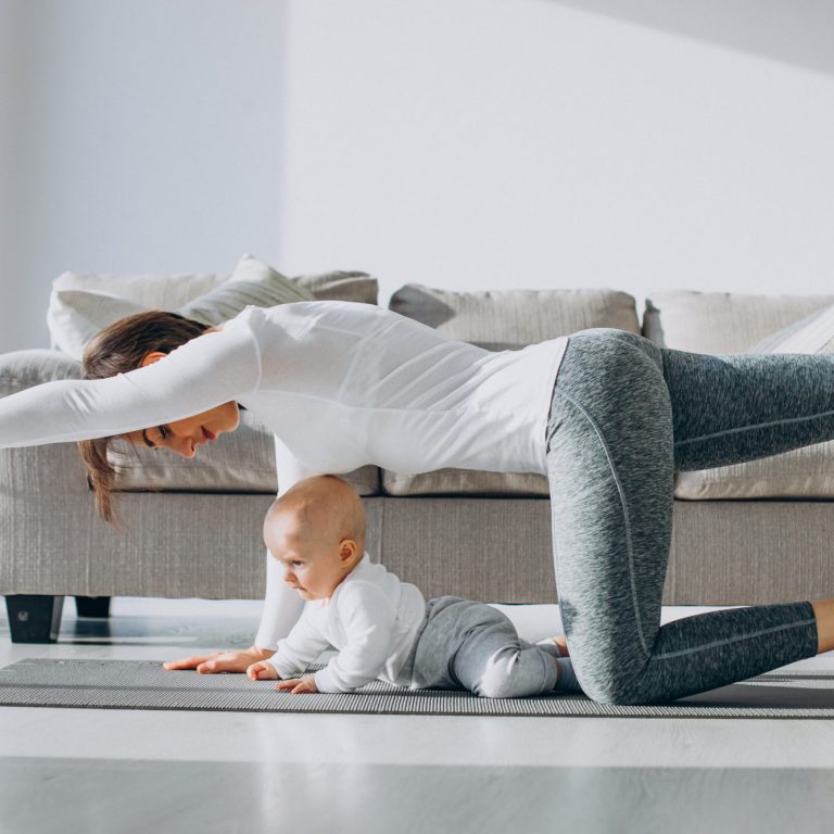 Une mère fait des exercices à quatre pattes près d'un bébé sur le tapis.